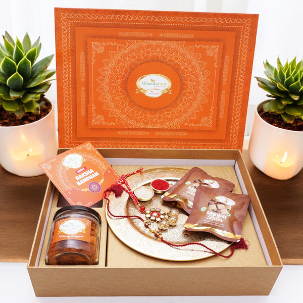 Ghasitaram Orange Hamper Box with Gold Pooja Thali, Bhaiya Bhabhi Rakhis, Card, Mewa Bites Pouches and Mixed Dryfruit Jar