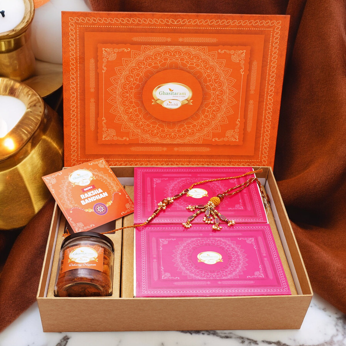 Ghasitaram Orange Hamper Box with Kaju Katli ,  Milk Cake, Bhaiya Bhabhi Rakhis, Card, and Mixed Dryfruit Jar