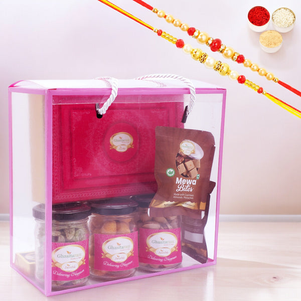 Transparent Gift Box with Kaju Katli, jars of crunchy cashews, paan raisins, pistachios and 5 Mewa Bites with 2 Rakhis