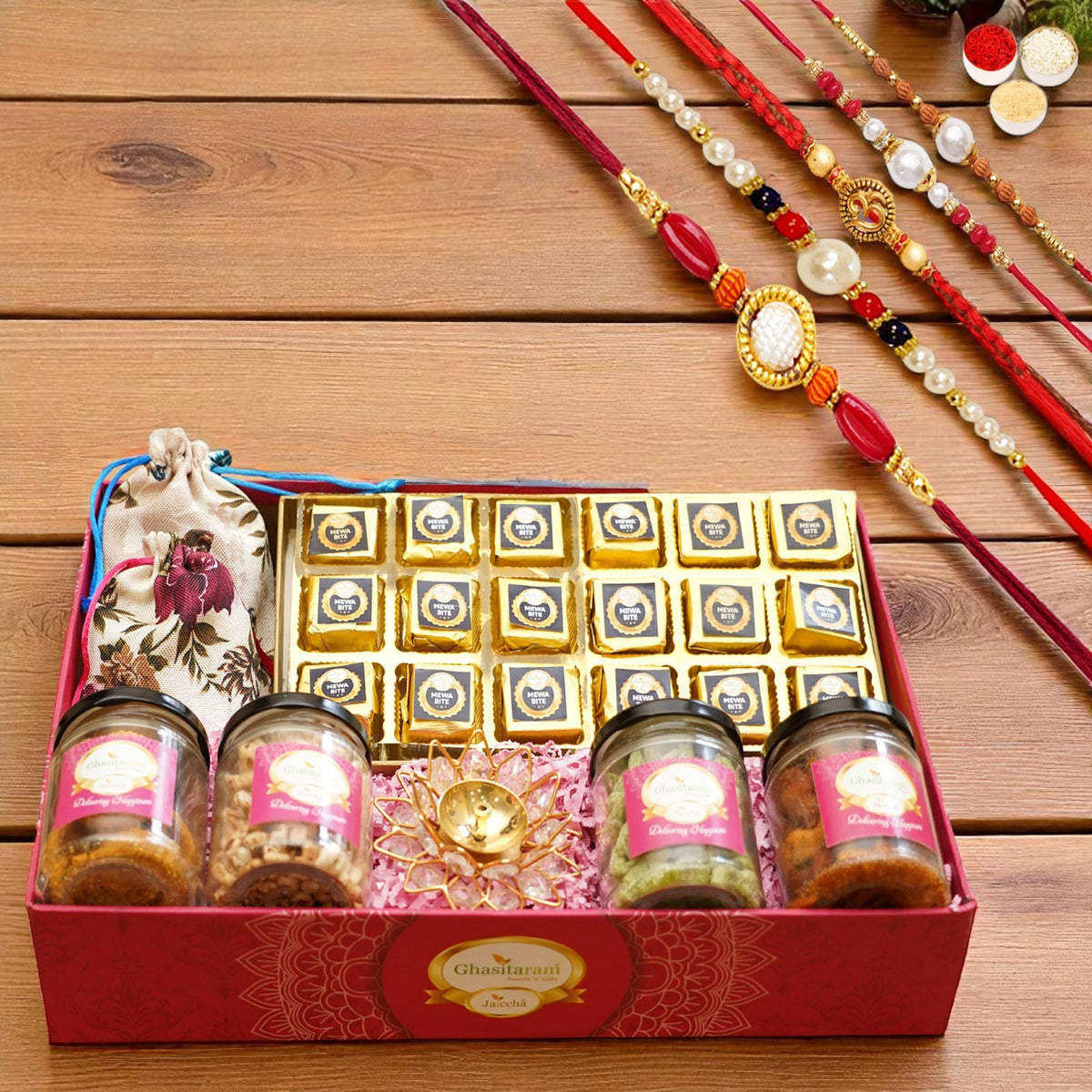 Big Pink tray of Mewa bites, jute pouches of mewa bites and anjeer bites, 2 jars of dryfruits, 2 jars of namkeen and diya with 5 rakhis